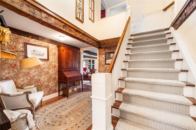 stairway with wood-type flooring and a towering ceiling