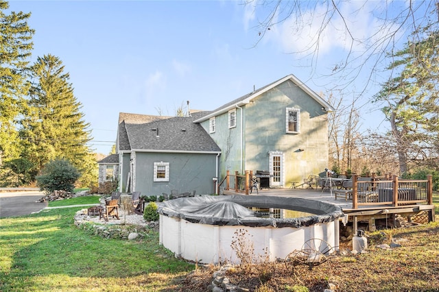 rear view of property featuring a lawn and a pool side deck