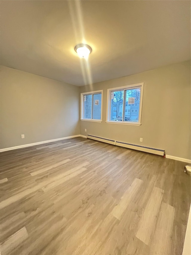 unfurnished room with light wood-type flooring and a baseboard heating unit