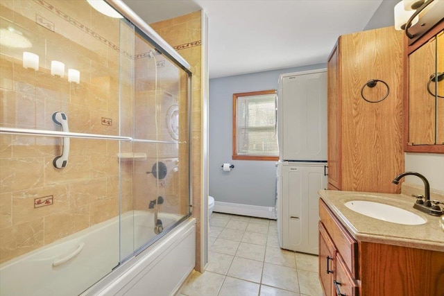 full bathroom with tile patterned floors, combined bath / shower with glass door, toilet, vanity, and stacked washer and clothes dryer