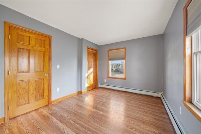 unfurnished bedroom featuring baseboard heating and light hardwood / wood-style flooring