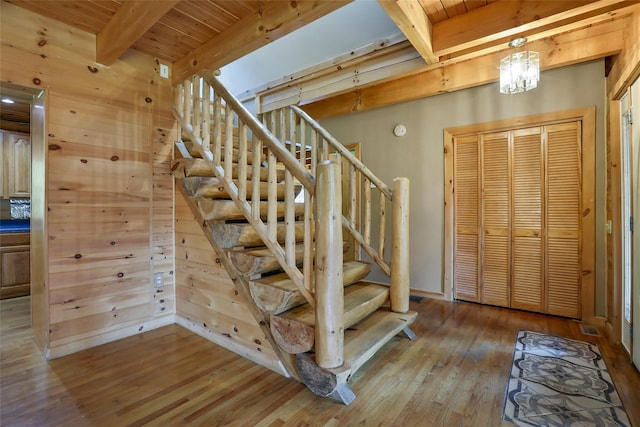 staircase featuring beamed ceiling, hardwood / wood-style floors, wooden walls, and wooden ceiling