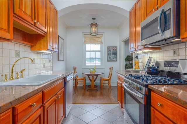 kitchen featuring dark stone countertops, light tile patterned flooring, sink, and stainless steel appliances