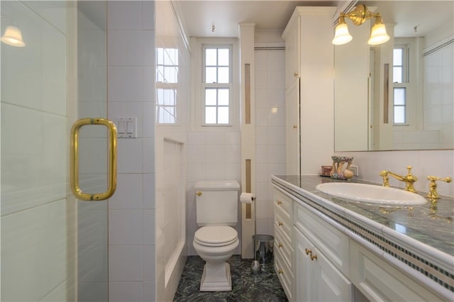 bathroom featuring vanity, toilet, tile walls, and a shower with shower door