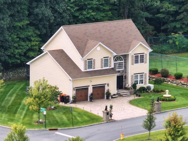 view of front of property featuring driveway, a garage, fence, and a front lawn