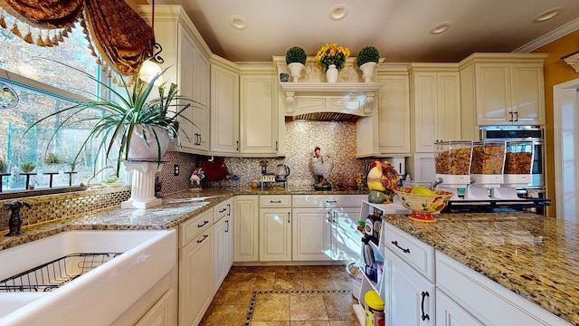 kitchen featuring light stone counters, stone tile floors, a sink, and decorative backsplash