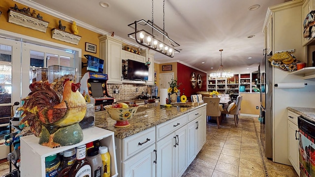 kitchen with light stone counters, ornamental molding, pendant lighting, and a sink