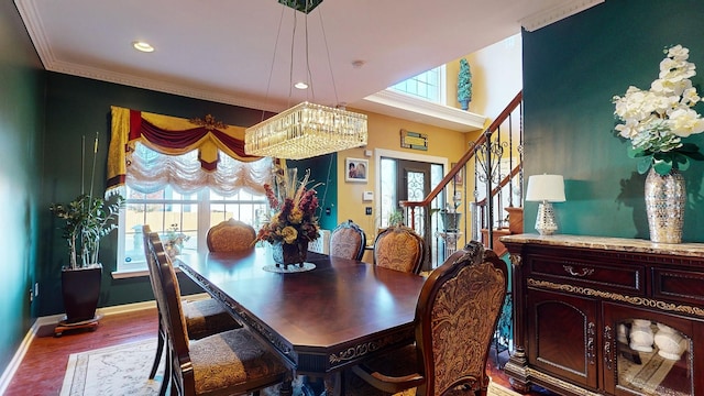 dining space featuring plenty of natural light, crown molding, baseboards, and wood finished floors