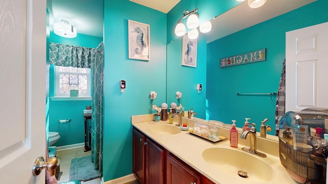 bathroom with double vanity, a sink, toilet, and baseboards