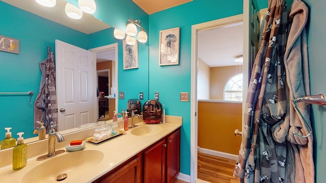 bathroom featuring double vanity, baseboards, a sink, and wood finished floors