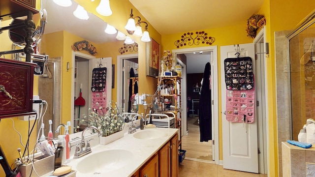 bathroom with double vanity, a tile shower, a sink, and tile patterned floors