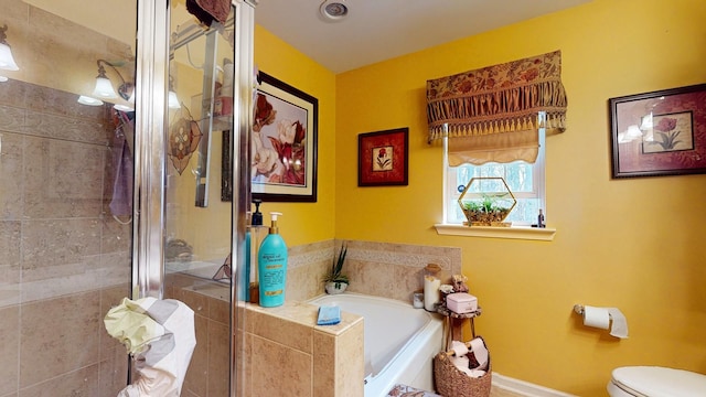 bathroom with a stall shower, baseboards, a garden tub, and toilet