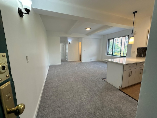 kitchen featuring kitchen peninsula, white cabinets, light colored carpet, and decorative light fixtures