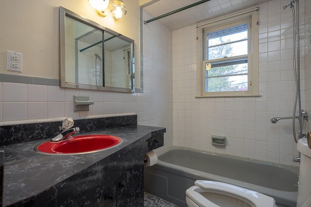 full bathroom featuring vanity, tiled shower / bath, tile walls, and toilet