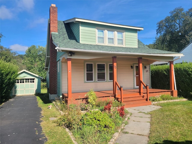 bungalow-style home featuring covered porch, an outbuilding, and a garage