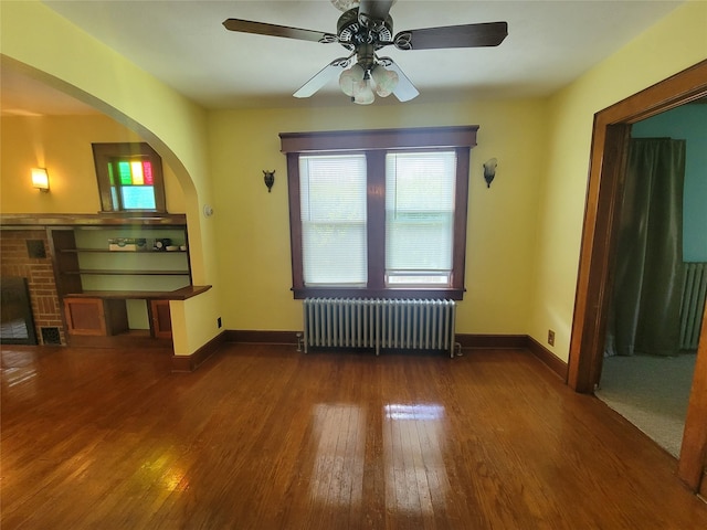 unfurnished living room featuring radiator heating unit, dark hardwood / wood-style flooring, and ceiling fan