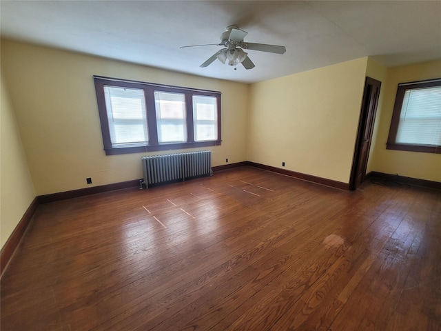 unfurnished room with radiator heating unit, ceiling fan, and dark wood-type flooring