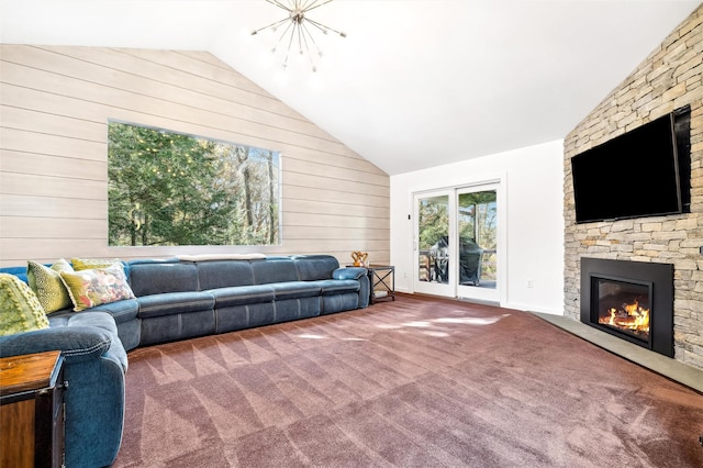 carpeted living room with wood walls, a fireplace, vaulted ceiling, and a notable chandelier