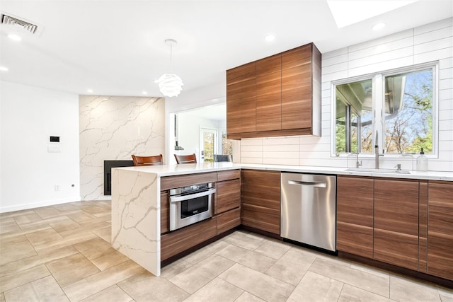 kitchen featuring a healthy amount of sunlight, kitchen peninsula, sink, and appliances with stainless steel finishes