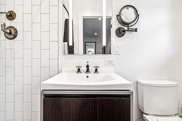 bathroom with a tile shower, vanity, and toilet