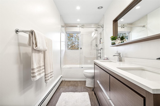 full bathroom with vanity, baseboard heating, shower / bath combination with glass door, hardwood / wood-style floors, and toilet