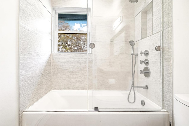 bathroom featuring toilet and combined bath / shower with glass door