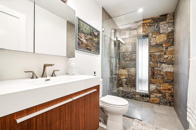 bathroom with tile patterned flooring, a tile shower, vanity, and toilet