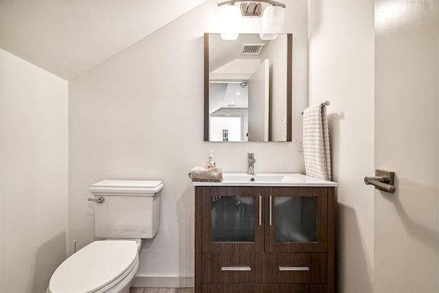 bathroom featuring vanity, wood-type flooring, lofted ceiling, and toilet