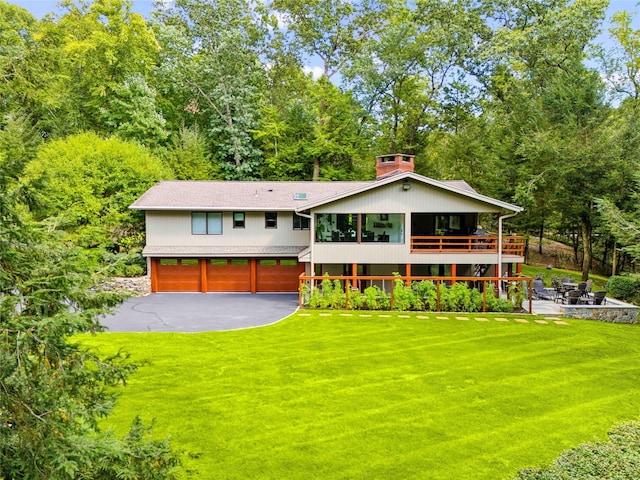 back of house with a yard, a garage, and a wooden deck