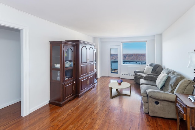 living room featuring baseboard heating and dark hardwood / wood-style floors