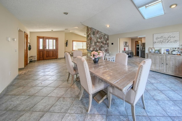 dining room with a textured ceiling and vaulted ceiling with skylight