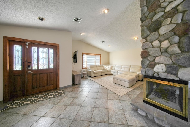 entryway featuring a fireplace, a textured ceiling, lofted ceiling, and tile patterned flooring