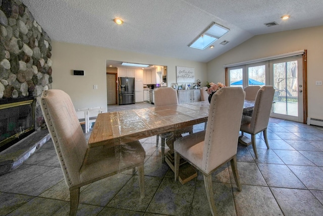 dining area featuring vaulted ceiling with skylight and a textured ceiling