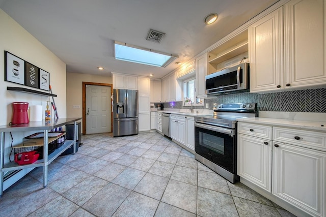 kitchen with white cabinets, stainless steel appliances, and a skylight