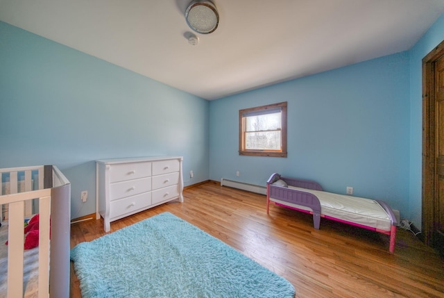 bedroom with a baseboard radiator and light wood-type flooring