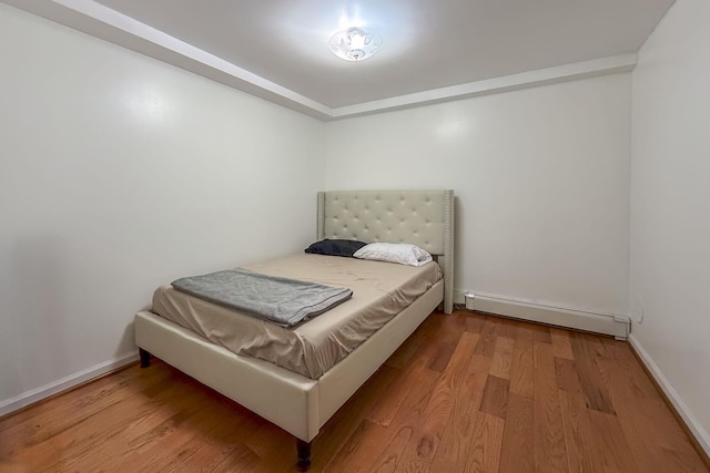 bedroom featuring baseboard heating and wood-type flooring