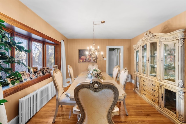 dining room featuring radiator, a chandelier, and light wood-type flooring