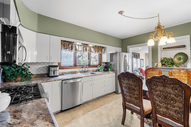 kitchen with pendant lighting, sink, white cabinetry, stainless steel appliances, and tasteful backsplash