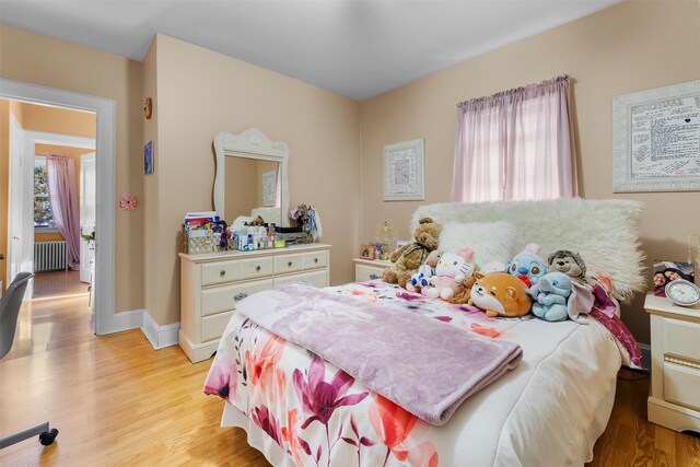 bedroom featuring radiator heating unit and light hardwood / wood-style floors