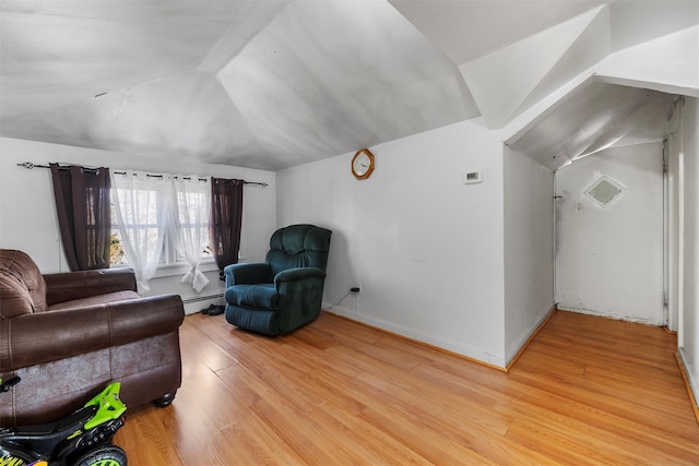 interior space with a baseboard heating unit, vaulted ceiling, and light wood-type flooring