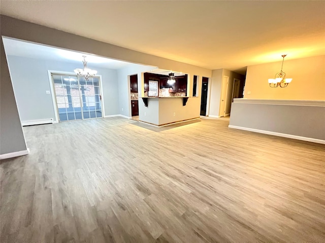 unfurnished living room featuring ceiling fan with notable chandelier, light hardwood / wood-style floors, and a baseboard radiator