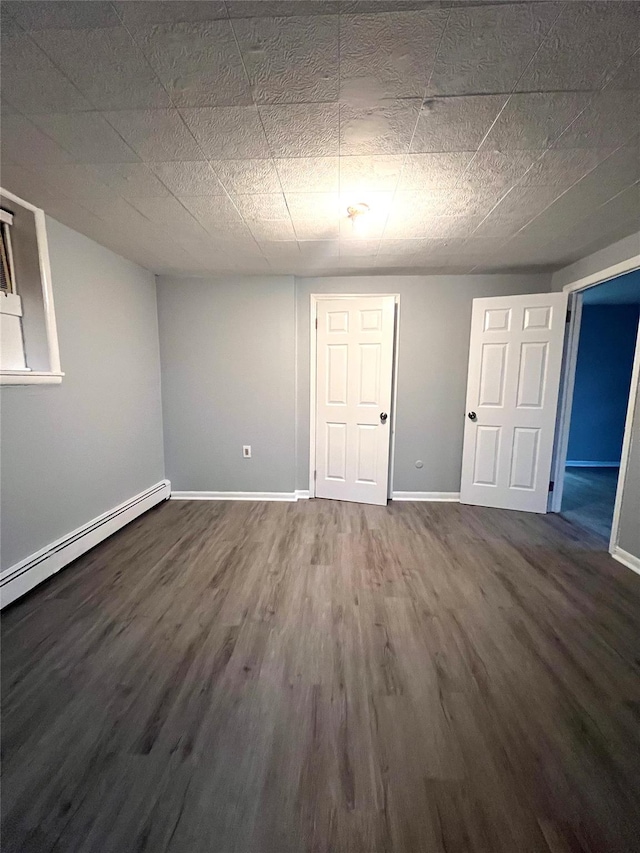 basement with dark hardwood / wood-style flooring and baseboard heating