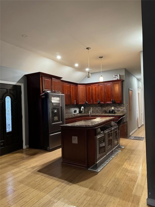 kitchen featuring light wood-type flooring, a center island, black refrigerator with ice dispenser, and backsplash