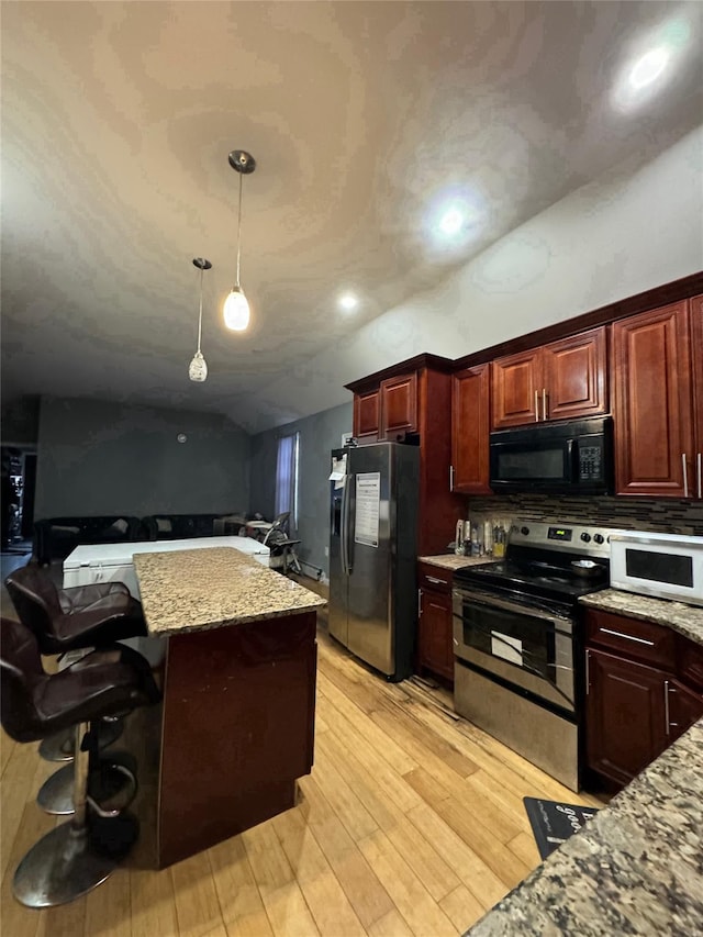 kitchen featuring a breakfast bar, stainless steel appliances, decorative light fixtures, light hardwood / wood-style flooring, and lofted ceiling