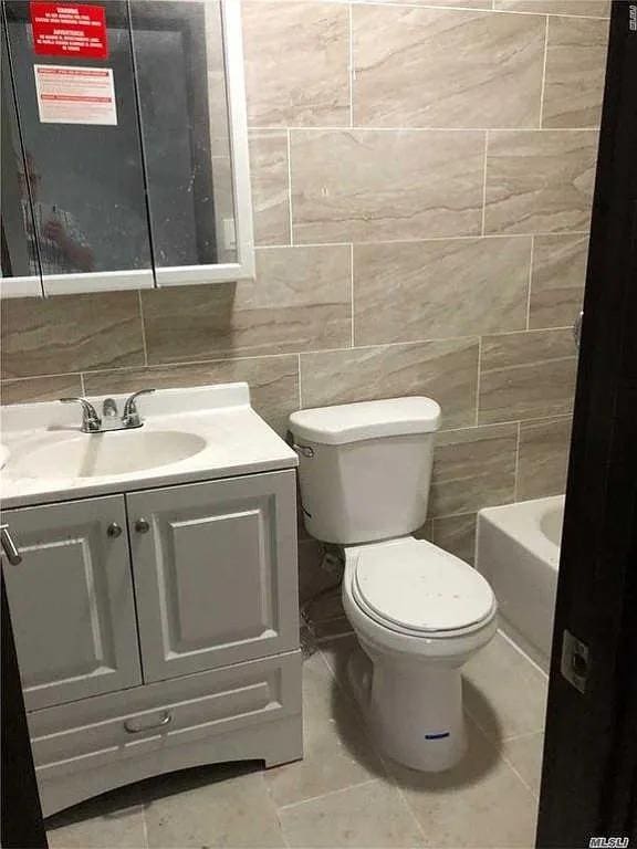 bathroom featuring vanity, tile walls, and a bathing tub