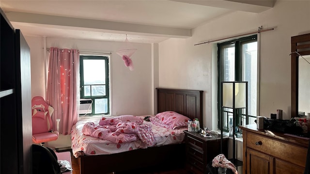 bedroom with cooling unit, beam ceiling, and multiple windows