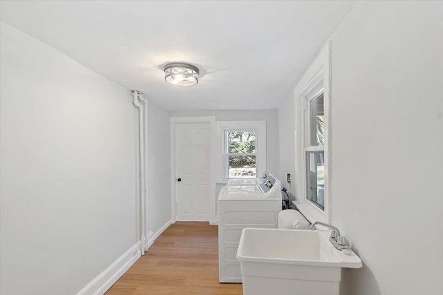 laundry room featuring washer and clothes dryer, sink, and light hardwood / wood-style flooring