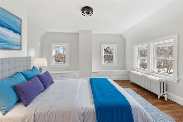 bedroom with radiator, vaulted ceiling, and dark hardwood / wood-style floors