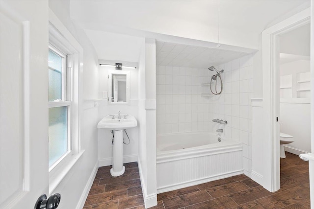 bathroom with a healthy amount of sunlight, toilet, and tiled shower / bath