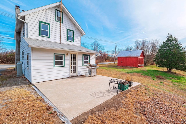 back of property with a storage shed, a patio area, and a lawn